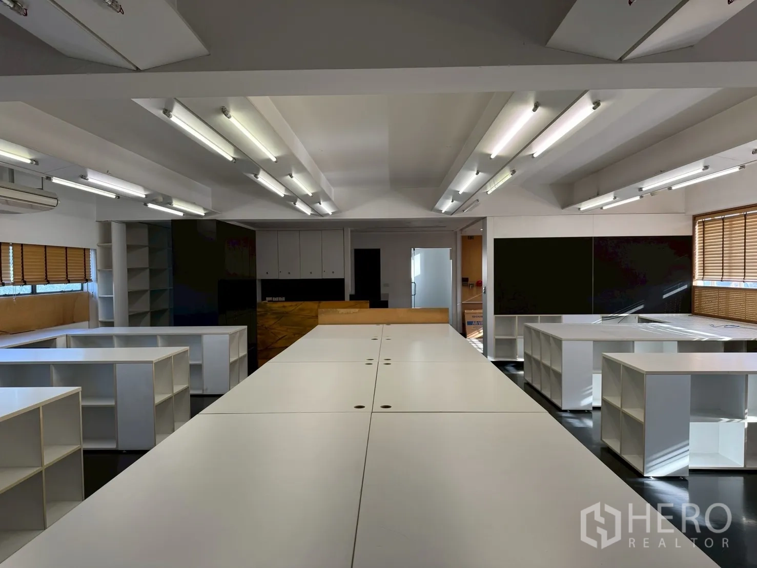 ออฟฟิศ for rent in Huai Khwang, Bangkok - โต๊ะทำงานยาวขนาดประชุม ล้อมรอบด้วยชั้นเก็บของช่องสี่เหลี่ยม ในสำนักงานสว่าง