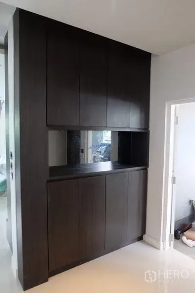 Detached House for rent in Bang Kapi, Bangkok - Tall dark wood built-in cabinet with storage and display niche beside an interior doorway.