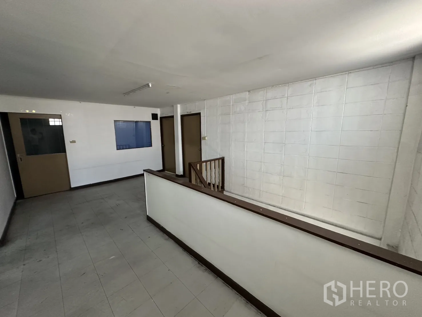 Warehouse for rent in Bang Na, Bangkok - Second-floor hallway overlooking stairwell with several doors.