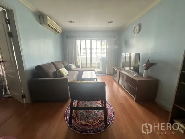 คอนโด ให้เช่าในWatthana, Bangkok - ห้องนั่งเล่นอบอุ่น โซฟาเอล ตู้วางทีวี พื้นไม้ และประตูกระจกสไลด์ออกสู่ระเบียง
