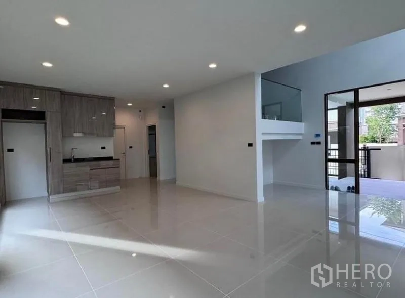 Detached House for rent in Bang Kapi, Bangkok - Open-plan living and dining area with glossy tile floors, recessed lighting, and a pantry corner.