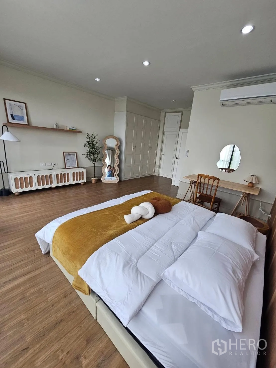 Townhouse for rent in Saphan Sung, Bangkok - Spacious master bedroom with wood flooring, wardrobes, work desk, and wall-shelf decor.