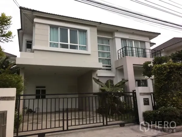 独立式住宅 出售在Saphan Sung, Bangkok - 曼谷沙攀颂区现代两层独栋别墅，设大窗与小阳台，前方有金属大门、铺装车道及有顶车位，周围绿化良好。