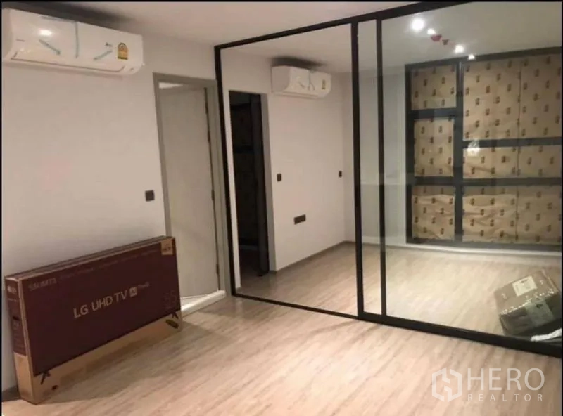 Condominium for sale in Khlong Toei, Bangkok - Bright unfurnished living area with light wood floors, a glass partition wall, and wall‑mounted air conditioner.