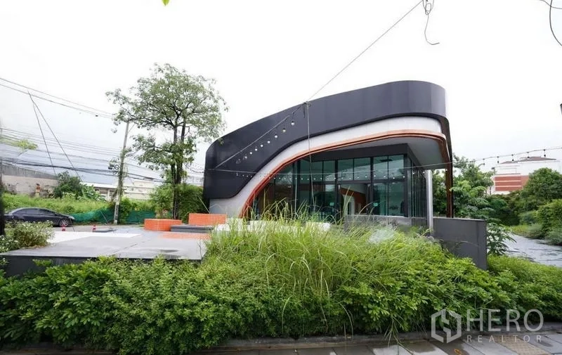 Standalone for rent in Bang Na, Bangkok - Street-side view of the standalone building amid mature greenery.