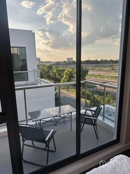 Detached House for rent in Saphan Sung, Bangkok - Upper-floor terrace with glass railing overlooking green views at sunset.