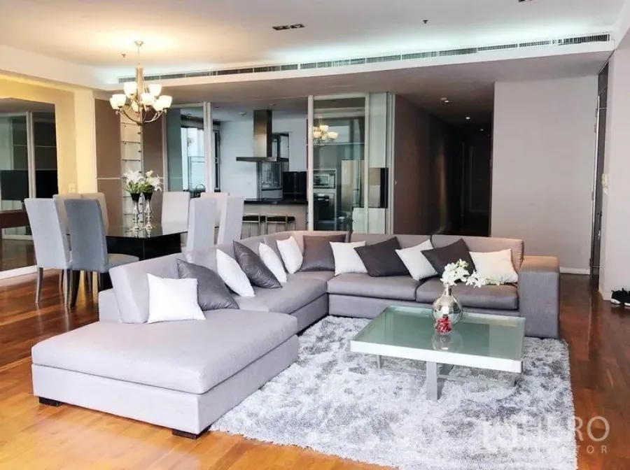 Condominium for rent in Khlong Toei, Bangkok - Spacious open-plan living room with large gray sectional sofa, rug and adjacent dining area.
