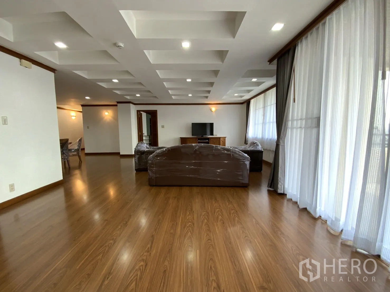 公寓 出租在Watthana, Bangkok - 宽敞客厅，木地板、格栅天花与落地窗，曼谷瓦塔那区公寓。