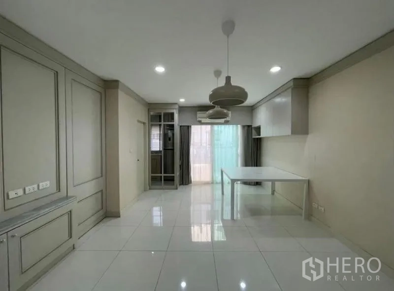 Townhouse for sale - Open-plan dining area with pendant lights, glossy white tile floors, and sliding glass doors.