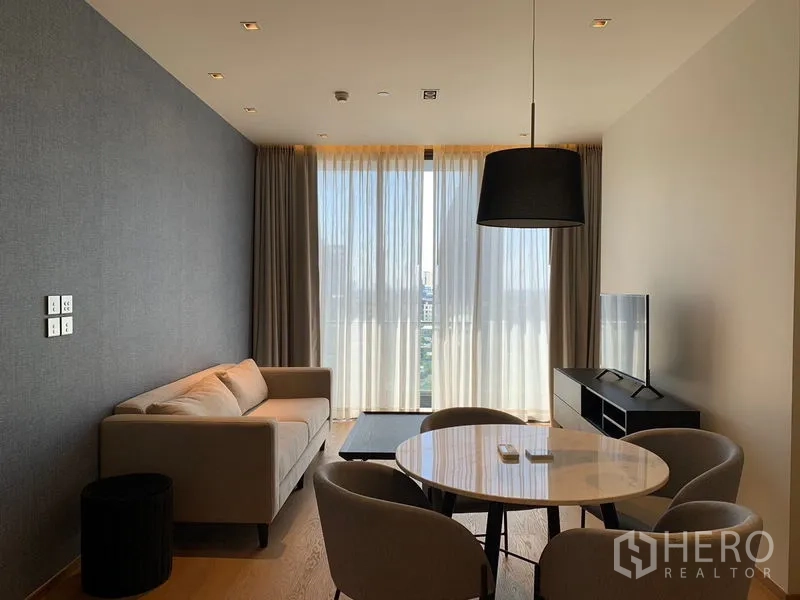 Condominium for rent in Khlong Toei, Bangkok - Wide view of living-dining zone with TV console and full-height windows letting in natural light.