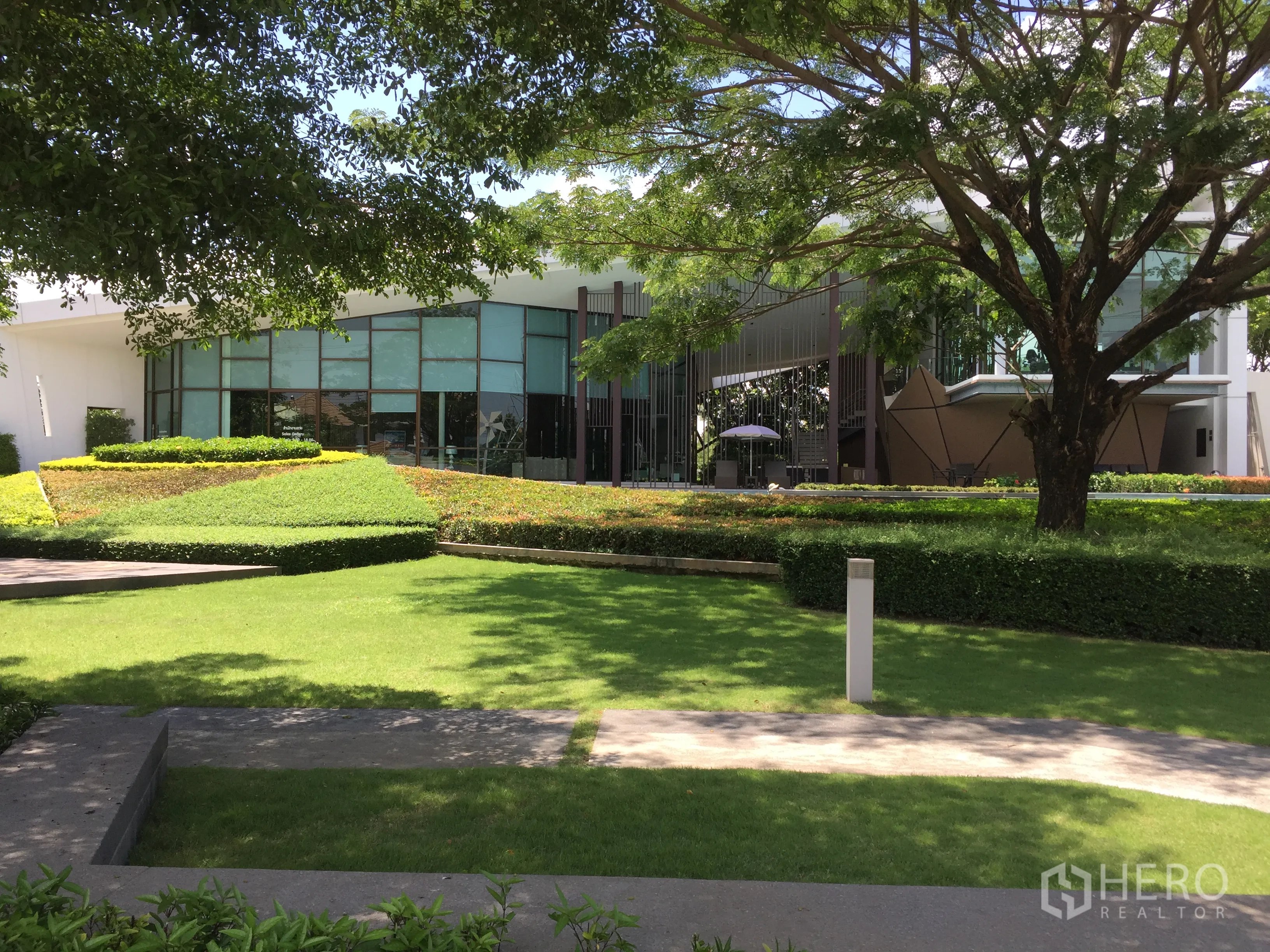 Detached House for rent or sale in Prawet, Bangkok - Estate clubhouse with manicured lawns, trees and modern architecture.