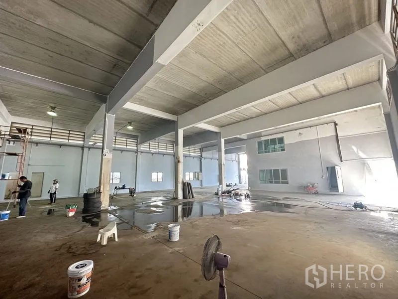 Factory for rent or sale in Bang Bua Thong, Nonthaburi - Expansive factory floor with tall beams, windows and wet-cleaned staging area.