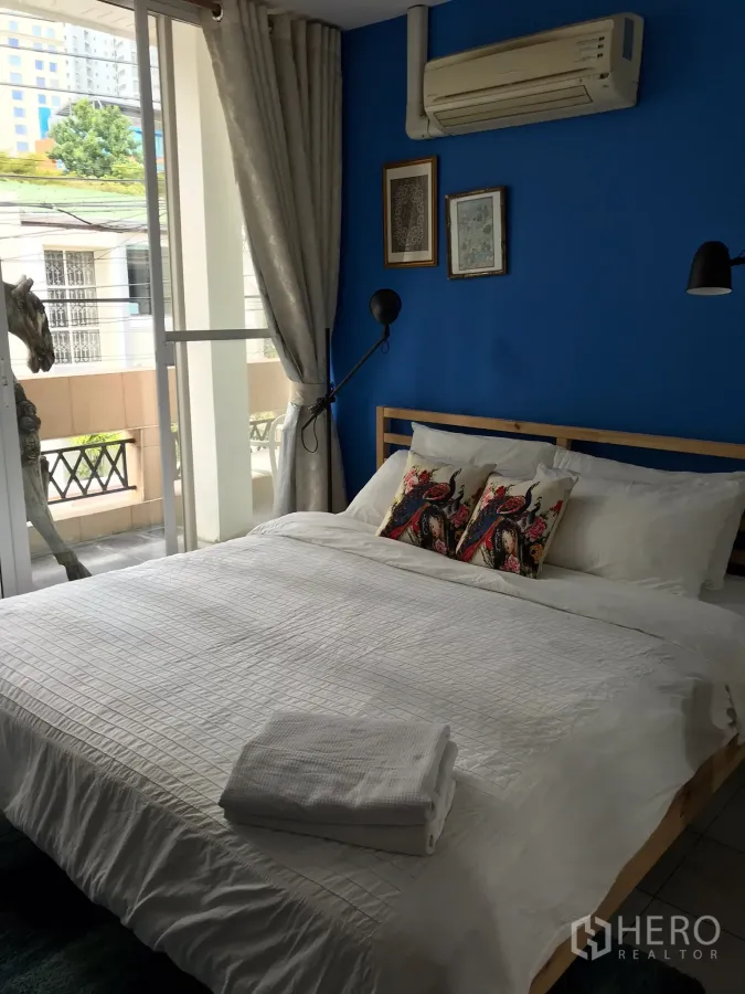 联排别墅 出租在Khlong Toei, Bangkok - 带蓝色特色墙的大窗卧室，配有空调。