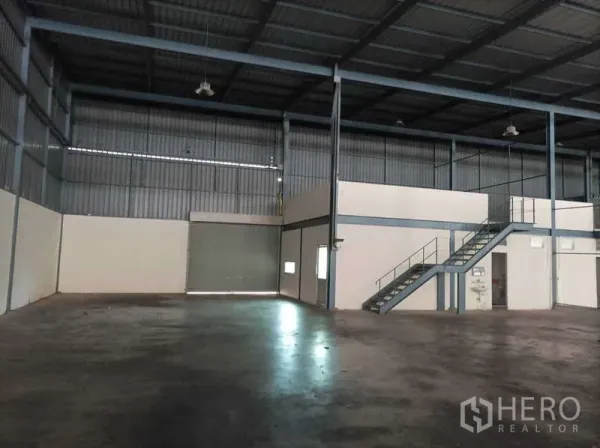 工厂 for rent in Ban Phaeo, Samut Sakhon - 高挑仓库内部，设夹层办公室、楼梯与卷闸门。