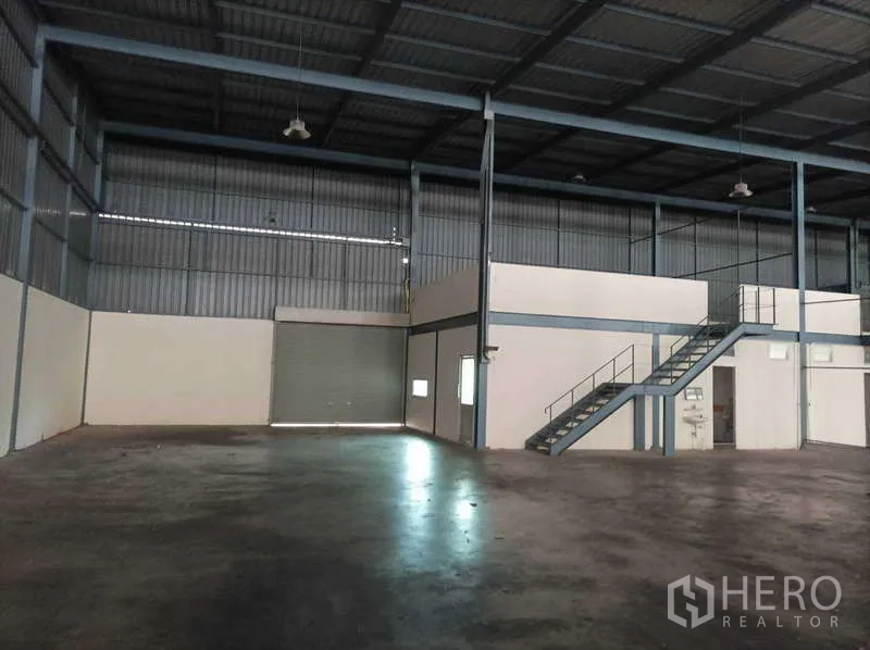 工厂 for rent in Ban Phaeo, Samut Sakhon - 高挑仓库内部，设夹层办公室、楼梯与卷闸门。
