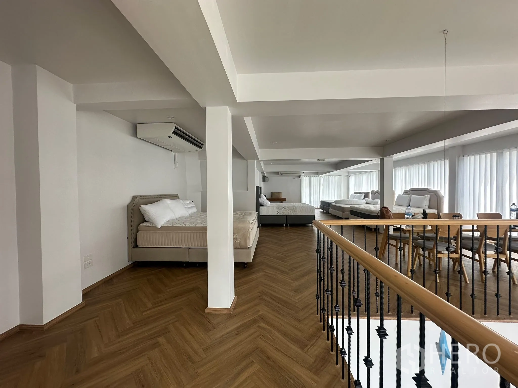 พื้นที่ขายของ for rent in Watthana, Bangkok - มุมมองบนชั้นลอยเห็นเตียง โต๊ะยาวพร้อมเก้าอี้ เครื่องปรับอากาศ และหน้าต่างรับแสง