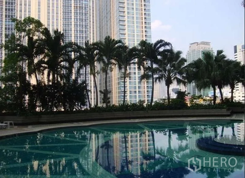 Condominium for sale in Pathum Wan, Bangkok - Outdoor swimming pool with palm trees and high-rise towers in the background