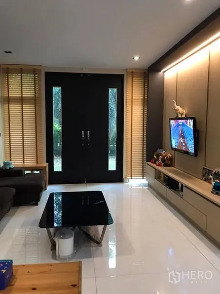 Detached House for sale in Saphan Sung, Bangkok - Bright living room with built-in TV wall, large double doors and glossy tile flooring.