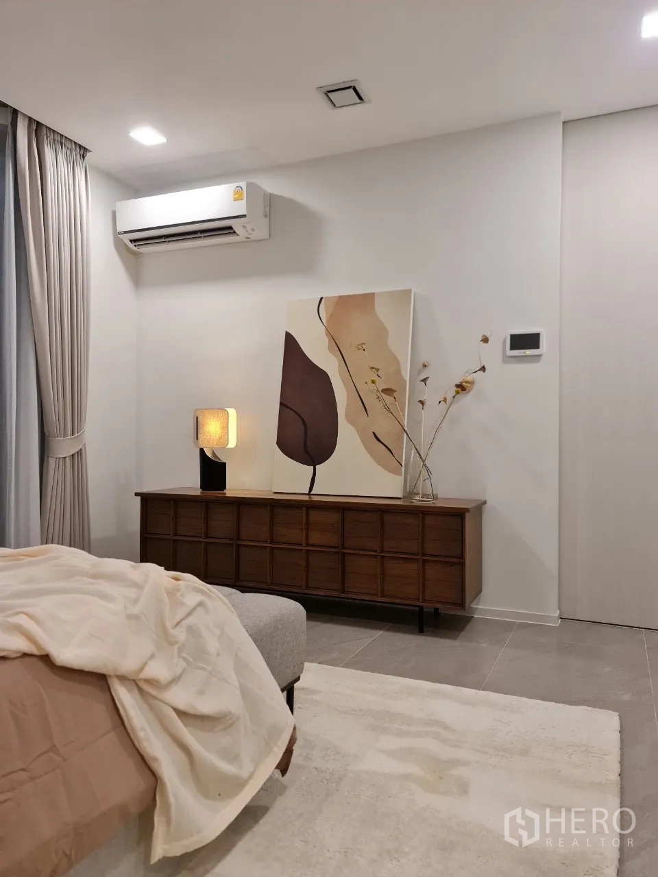 Detached House for rent in Saphan Sung, Bangkok - Bedroom corner with long wooden console, wall art and air conditioner.