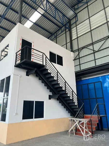 货栈 出租在Lat Krabang, Bangkok - 夹层办公室与黑色金属楼梯，位于高挑钢结构屋顶下。