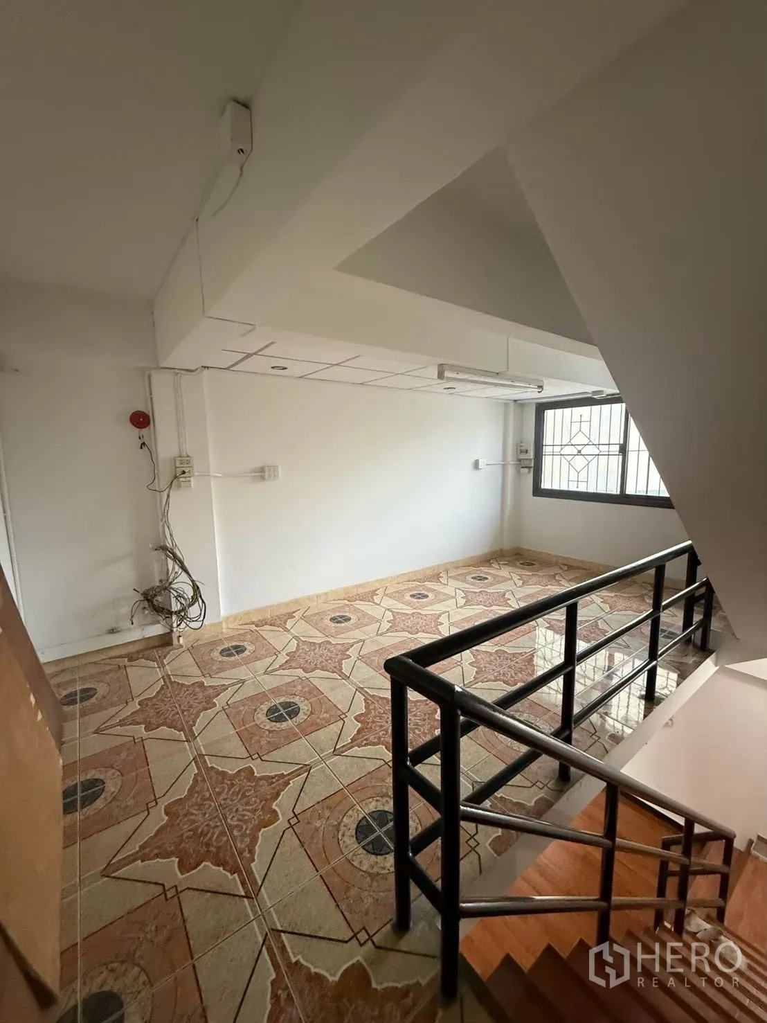 Shophouse for rent in Pak Kret, Nonthaburi - Upper landing with patterned floor tiles and black railing.