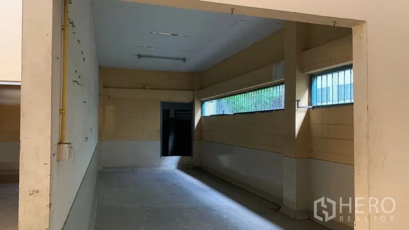 Warehouse for rent in Mueang Nakhon Pathom, Nakhon Pathom - Long ancillary room with high barred windows and tiled floor inside the warehouse.