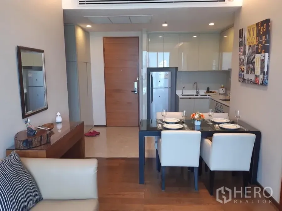 Condominium for rent in Khlong Toei, Bangkok - Compact modern kitchen and a four-seat dining table positioned by the entry door.