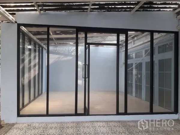 Detached House for rent in Watthana, Bangkok - Glass-enclosed room with black aluminum sliding doors opening to a tiled patio.