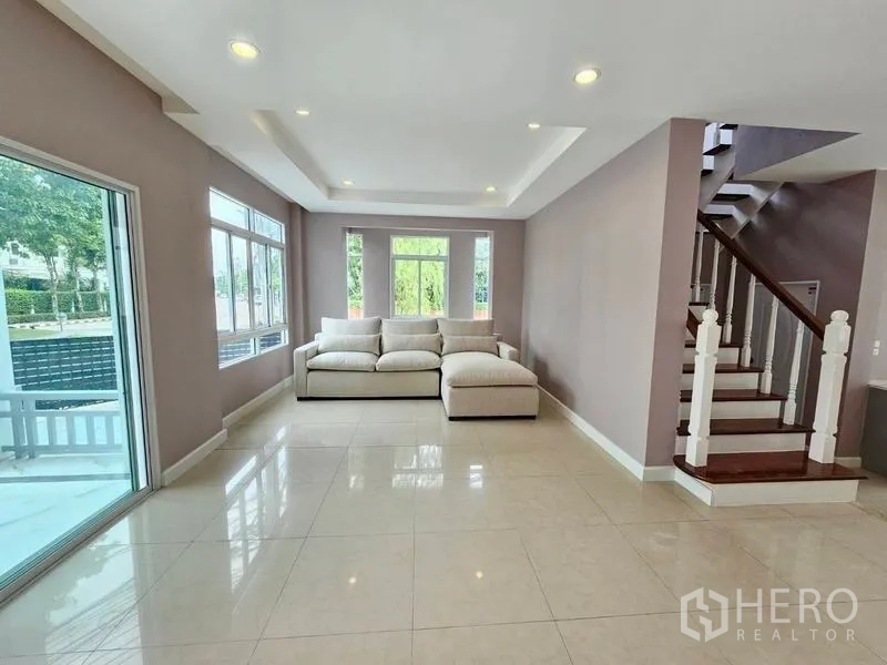 独立式住宅 出售在Pak Kret, Nonthaburi - 采光充足的客厅，落地滑门、嵌灯与木质楼梯