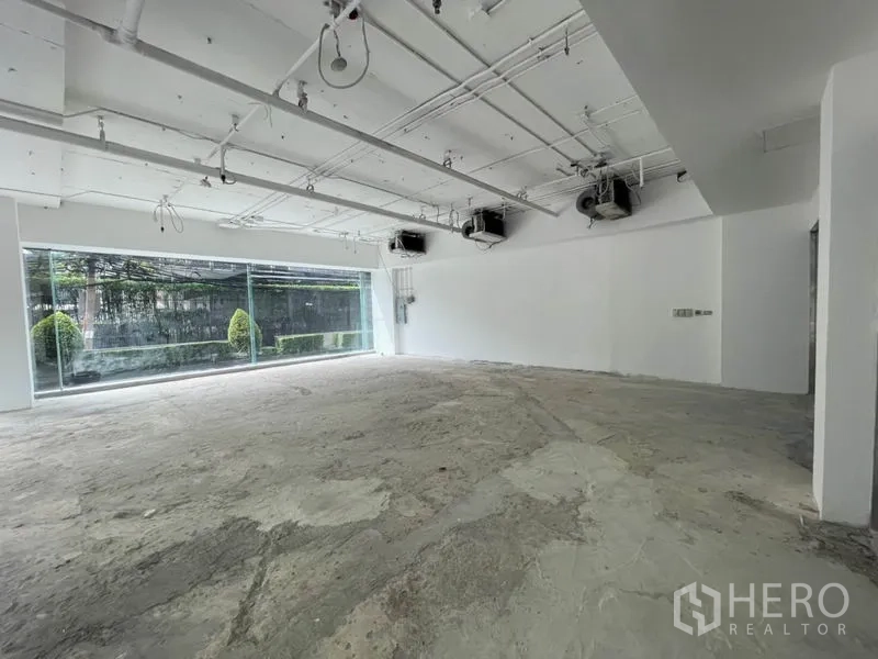 零售空间 出租在Watthana, Bangkok - 未装修商铺壳体，外露风管、大型展示窗与吊顶空调机组。