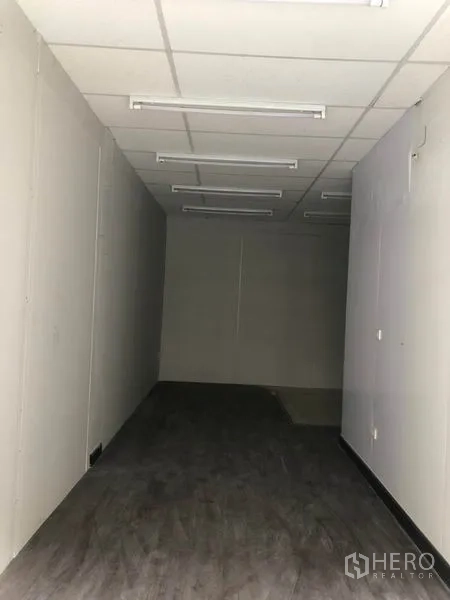 Retail Space for rent in Khlong Toei, Bangkok - Deep interior view of vacant unit with multiple fluorescent lights and dark flooring.