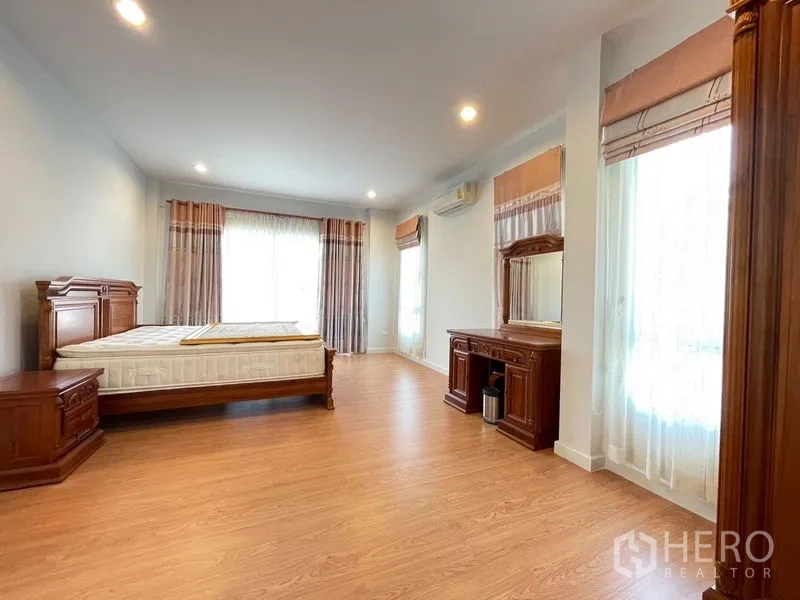 Detached House for sale in Lat Krabang, Bangkok - Large master bedroom with wooden furniture, bedside tables, dressing table and laminate flooring.
