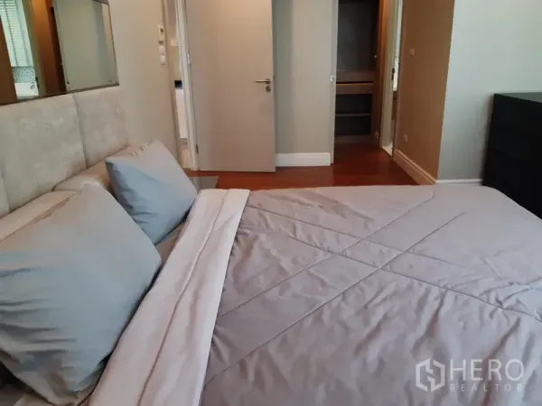 Condominium for rent or sale in Khlong Toei, Bangkok - Bedroom view toward the closet and doorway with warm wood flooring and neutral decor.