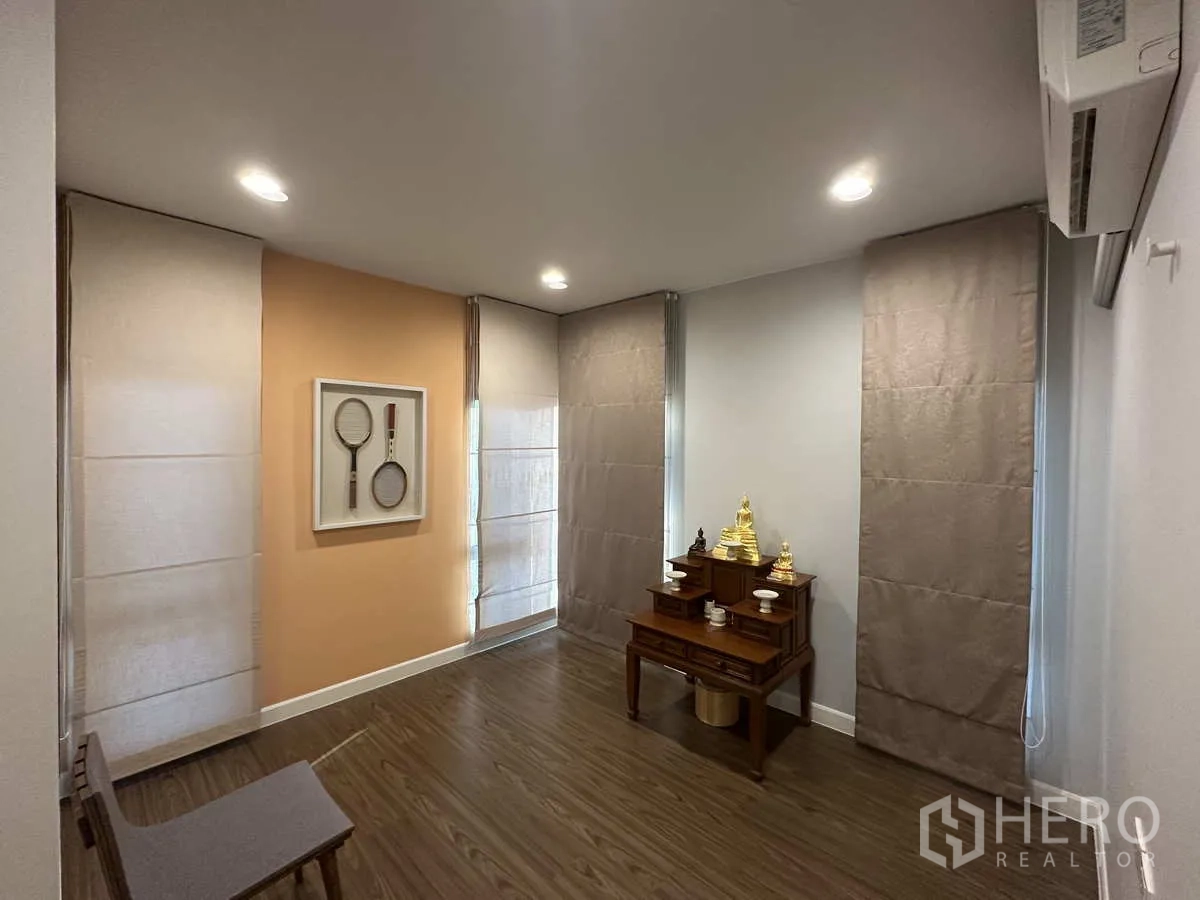 Detached House for rent or sale in Lam Luk Ka, Pathum Thani - Multipurpose or prayer room with warm accent wall and wood floors.