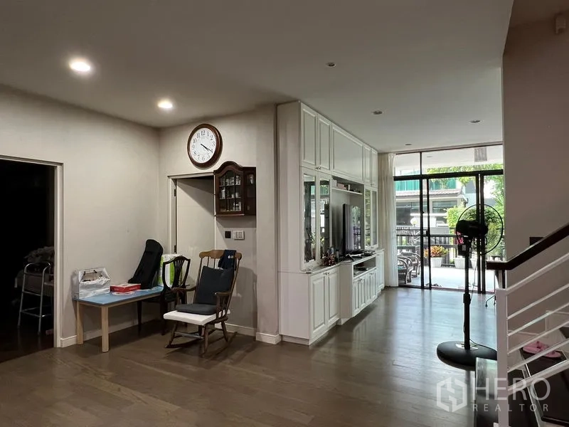 Detached House for sale in Bang Kapi, Bangkok - Ground-floor living area with built-in media wall, staircase and sliding doors to the terrace.