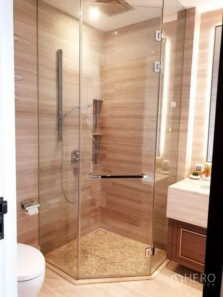 Condominium for rent or sale in Watthana, Bangkok - Modern bathroom featuring a glass-enclosed shower, wall-mounted fixtures and stone tiles.