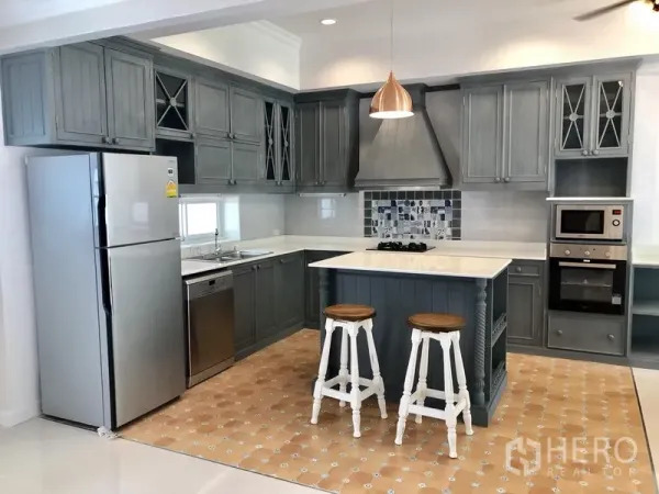 Detached House for rent in Mueang Samut Prakan, Samut Prakan - Shaker-style grey kitchen with island, white countertops and stainless appliances.