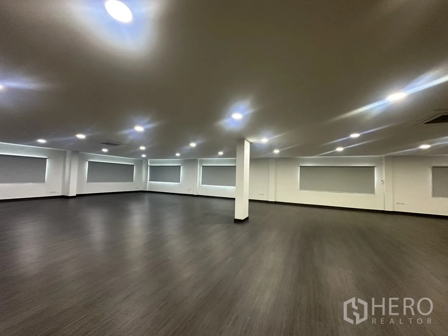 办公室 for rent in Yan Nawa, Bangkok - 宽敞开放式办公区，深色木纹地板、白墙、嵌入式LED筒灯与卷帘窗。