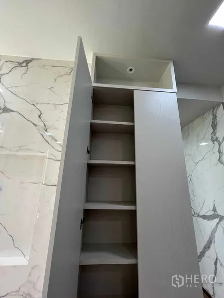 Condominium for rent in Watthana, Bangkok - Tall built-in storage cabinet with open shelves set against a marble feature wall.