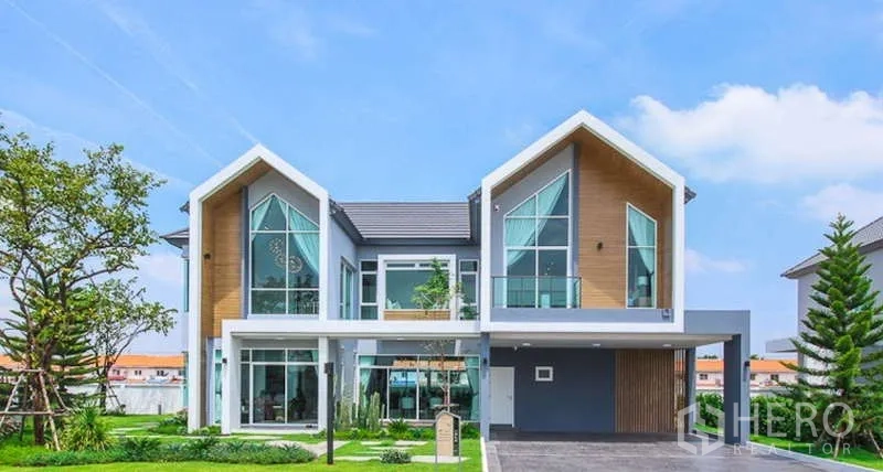 Detached House for sale in Lam Luk Ka, Pathum Thani - Front elevation of a contemporary detached house with expansive glazing and lawn.