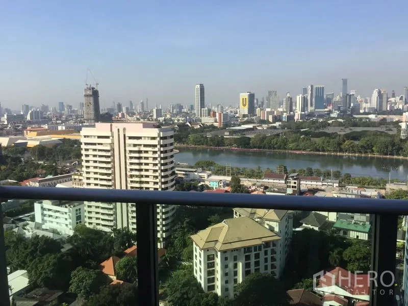 Condominium for rent in Khlong Toei, Bangkok - High‑floor balcony view of Bangkok skyline and Benjakitti Park lake.