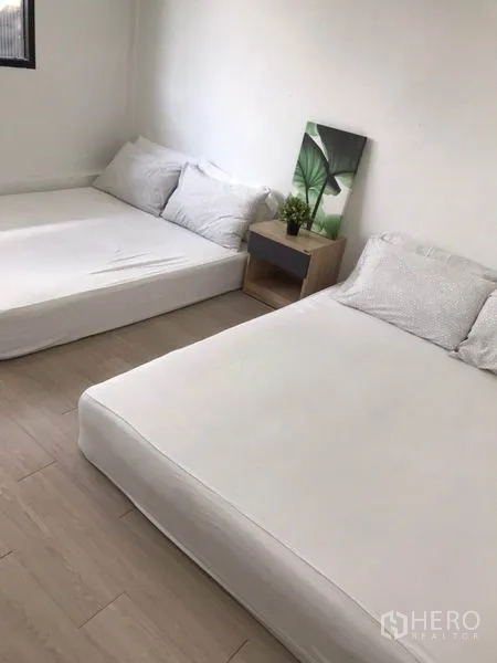 Home Office for rent - Spacious bedroom with two low beds, bedside table and simple wall art.