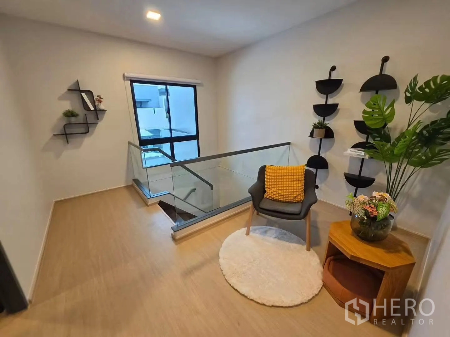 Townhouse for rent in Bang Phli, Samut Prakan - Upstairs landing nook with chair, side table, decor shelves, and glass balustrade.