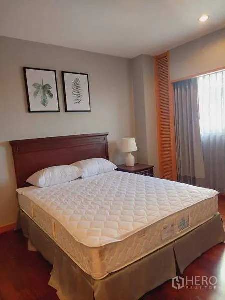 Apartment for rent - Bright bedroom with a wooden headboard, bedside lamp, framed botanical art and wood flooring.