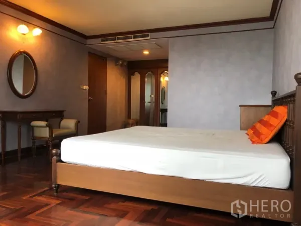 Condominium for rent in Khlong Toei, Bangkok - Bedroom angle showing bed, mirrored wardrobe and dressing table with soft lighting.