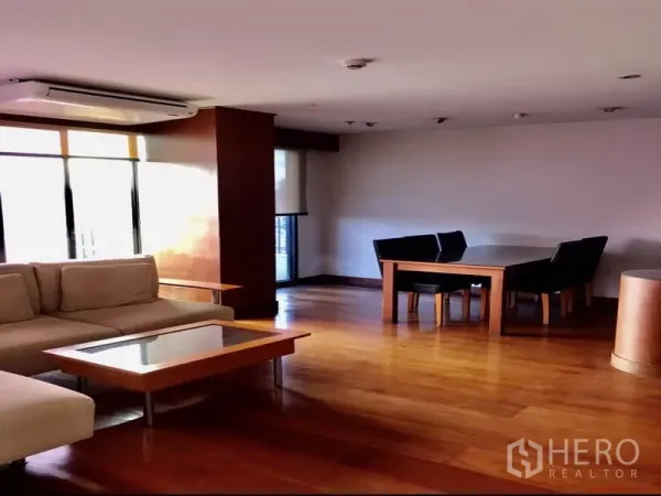 公寓 出租或出售在Watthana, Bangkok - 宽敞客餐厅，木地板，L形沙发和大窗户。
