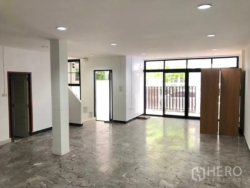 Townhouse for rent in Watthana, Bangkok - Ground-floor open space with staircase, large sliding doors and abundant natural light.