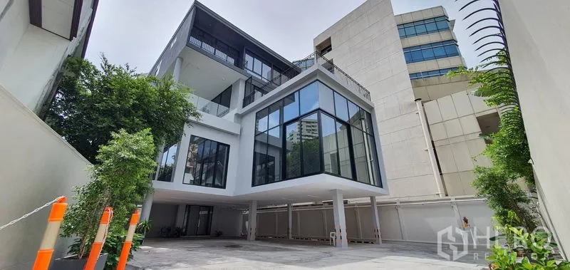 带办公室的家 出租或出售在Watthana, Bangkok - 当代玻璃立面家用办公楼，前方车道与绿植。