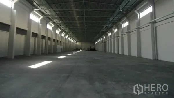 Warehouse for rent in Bang Sao Thong, Samut Prakan - Empty clear-span warehouse hall with high ceiling, ventilation windows, and concrete floor.