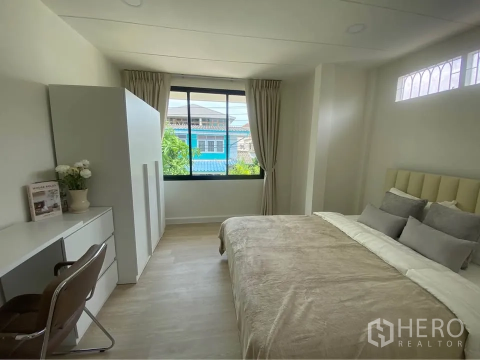 บ้านเดี่ยว for rent in Huai Khwang, Bangkok - ห้องนอนสว่างพร้อมหน้าต่างบานใหญ่ โต๊ะทำงาน ตู้เสื้อผ้า และเตียงคู่โทนอบอุ่น